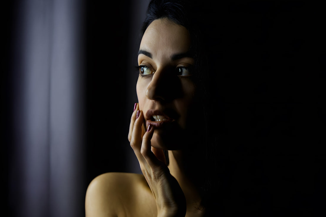 Woman with hand on face in dramatic lighting